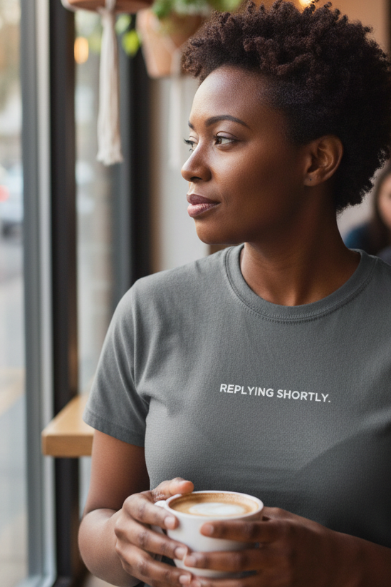 African American woman in coffee shop wearing REPLYING SHORTLY shirt